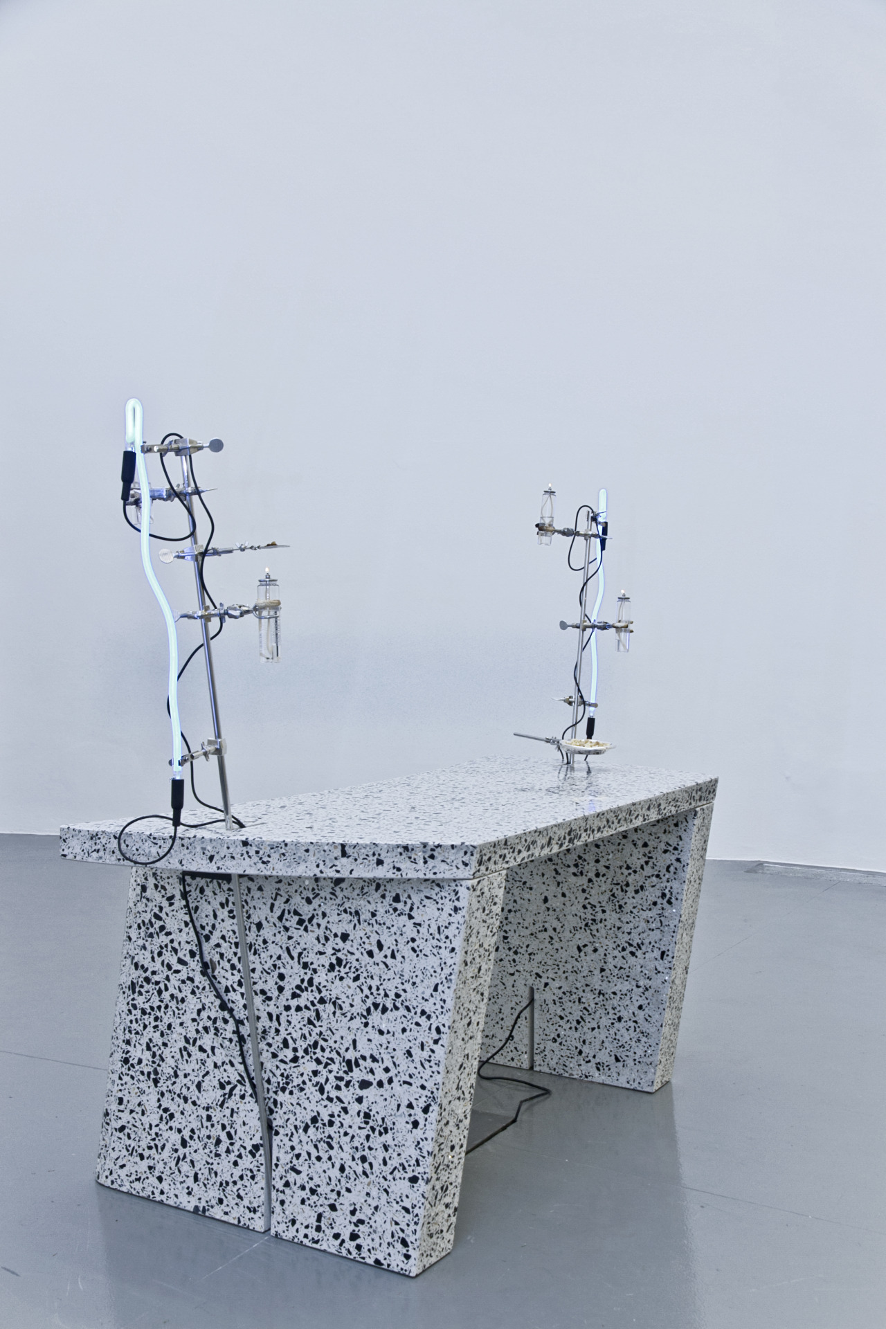 A day dream about the authority of a heavy desk, about other vocations spent behind one ordering certain men around, about domineering and maybe reclining slowly, exhaling, 2014. Terrazzo, stainless steel, laboratory hardware, neon lights, transformers, paraffin lamps, mica, frankincense, sterling silver Tiffany dish. Variable dimensions. Courtesy of the artist.