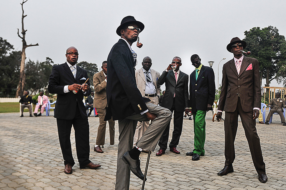 Daniele Tamagni. "Sapeurs posing in front of Memorial Savorgnan de Brazz, Brazzaville," 2008. Digital print. 25.9 x 35.8 in