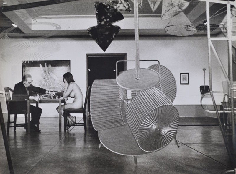 Julian Wasser. "Duchamp making a chess move in distance, Duchamp Retrospective, Pasadena Art Museum, 1963." Vintage gelatin silver print. 10 x 13.5” courtesy Robert Berman/E6 Gallery.