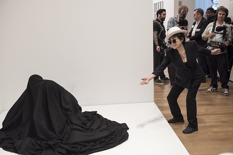 Yoko Ono interacting with people activating Bag Piece (1964), a participatory work in "Yoko Ono: One Woman Show, 1960-1971," on view at MoMA, May 17 -September 7, 2015. Photo by Ryan Muir © Yoko Ono