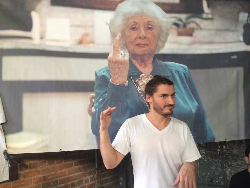 Ethan Rafal at Rob Pruitt’s Flea Market, standing in front of an image of his grandmother.